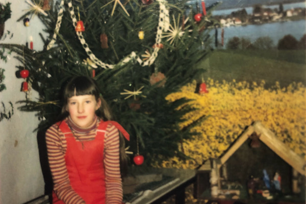 Mädchen mit langen Zöpfen sitzt nachdenklich vor dem Christbaum – Symbol für verlorene Freude und die Suche nach Anerkennung.