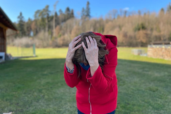 Symbolbild für Angstbewältigung: Frau mit Händen über dem Kopf, nach vorne gebeugt – Atmung gegen Beklemmung.