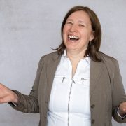 Anita Griebl lacht voller Freude in die Kamera, die Hände offen zum Empfang – Symbolbild für Befreiung, Selbstannahme und das Loslassen alter Glaubenssätze.