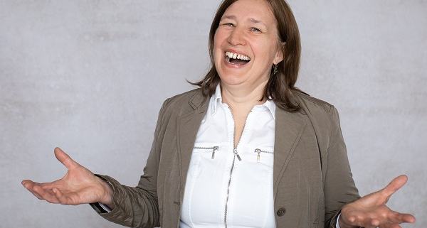 Anita Griebl lacht voller Freude in die Kamera, die Hände offen zum Empfang – Symbolbild für Befreiung, Selbstannahme und das Loslassen alter Glaubenssätze.