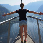 Junge Frau steht mit ausgebreiteten Armen auf einem Steg am Wasser und symbolisiert Freiheit und innere Leichtigkeit.