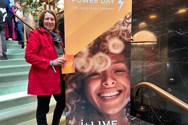 Anita Griebl steht auf einer Treppe vor einem Plakat des Powerdays.