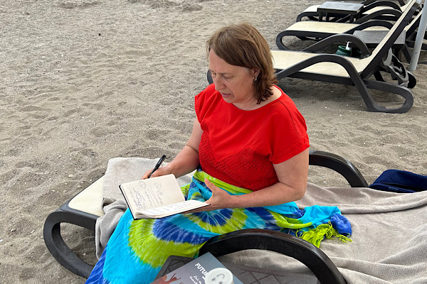 Anita Griebl sitzt am Strand auf einer Liege mit Notizbuch und Stift – Symbol für Selbstreflexion, innere Blockaden und Probleme, die ohne Zugang zu Gefühlen unlösbar wirken.