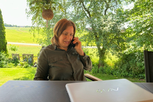 Heilenergetikerin Anita Griebl bei digitaler Energiearbeit in der Natur – mit Laptop und Telefon.