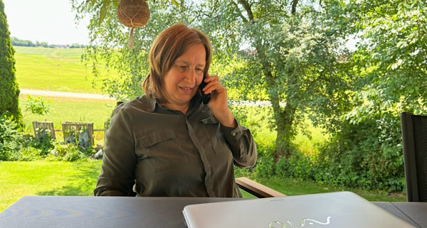Heilenergetikerin Anita Griebl bei digitaler Energiearbeit in der Natur – mit Laptop und Telefon.