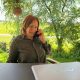 Heilenergetikerin Anita Griebl bei digitaler Energiearbeit in der Natur – mit Laptop und Telefon.