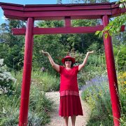 m Nepal-Park unter dem roten Tor erhebt sich die Energie – Anita Griebl in einem Moment der spirituellen Öffnung und bewussten Präsenz.