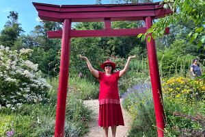 m Nepal-Park unter dem roten Tor erhebt sich die Energie – Anita Griebl in einem Moment der spirituellen Öffnung und bewussten Präsenz.
