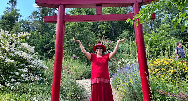 m Nepal-Park unter dem roten Tor erhebt sich die Energie – Anita Griebl in einem Moment der spirituellen Öffnung und bewussten Präsenz.