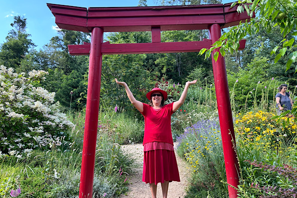 m Nepal-Park unter dem roten Tor erhebt sich die Energie – Anita Griebl in einem Moment der spirituellen Öffnung und bewussten Präsenz.