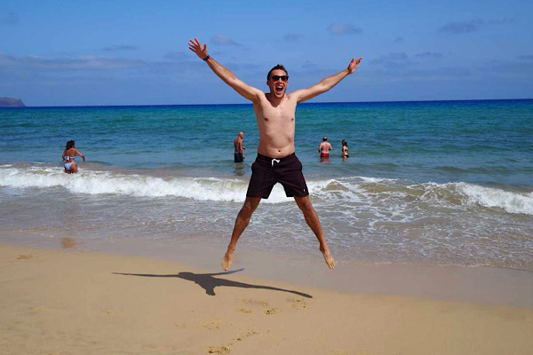 Neue Energie - energievoll am Meer. Ein junger Mann springt am Strand vor Energie.
