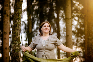 Anita Griebl steht im Wald mit fließendem Kleid und Tuch in den Händen – ein Moment der Intuition, Naturverbundenheit und inneren Klarheit.