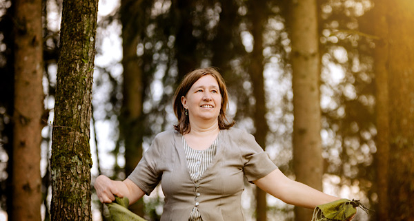 Anita Griebl steht im Wald mit fließendem Kleid und Tuch in den Händen – ein Moment der Intuition, Naturverbundenheit und inneren Klarheit.