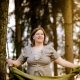 Anita Griebl steht im Wald mit fließendem Kleid und Tuch in den Händen – ein Moment der Intuition, Naturverbundenheit und inneren Klarheit.
