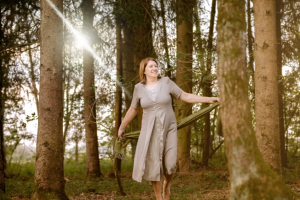 Anita Griebl barfuß im Wald, von Licht durchflutet – Moment der Selbstverbundenheit, Bewegung und heilenergetischer Präsenz.