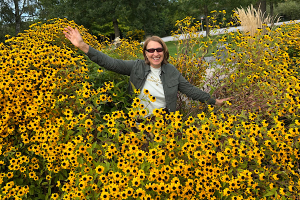 Anita Griebl mit Sonnenbrille sitzt zwischen gelben Blüten – ein Moment der stillen Freude und inneren Fülle.