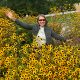 Anita Griebl mit Sonnenbrille sitzt zwischen gelben Blüten – ein Moment der stillen Freude und inneren Fülle.