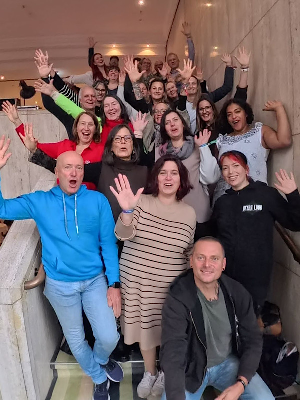 Teamfoto auf der Treppe – Anita Griebl mit einem großen Kreis von Partner:innen, getragen von Verbundenheit und Business mit Herz.