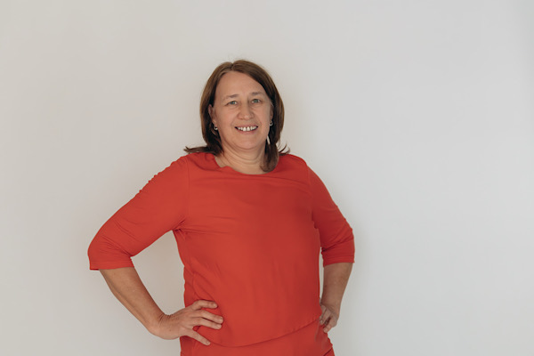 Foto von Anita Griebl: rotes Shirt, selbstbewusste Haltung mit Händen in der Hüfte – persönliches Statement mit Präsenz und Klarheit.