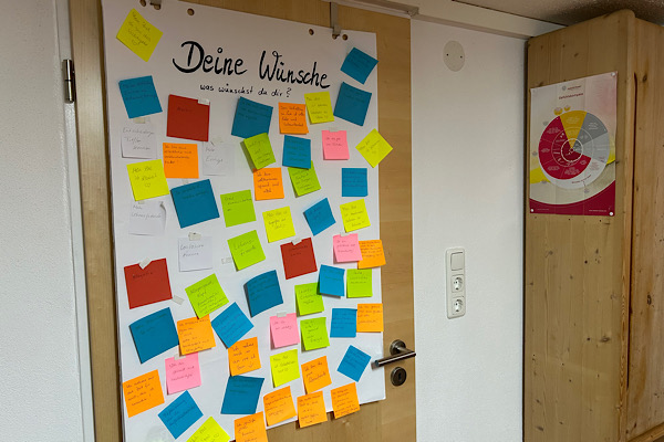 Türplakat mit farbenfrohen Zetteln, auf denen die Wünsche der Teilnehmerinnen des 10. Frei-Sein-Seminars leuchten – ein Symbol für gelebte Wandlung.