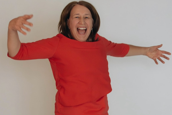 Anita Griebl springt in der Natur in die Luft und lacht, voller Leichtigkeit und Energie.