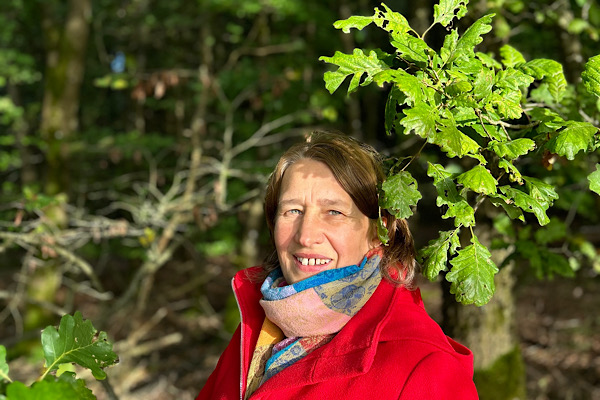 Anita Griebl blickt zwischen Eichenblättern hervor – Ausdruck von Nähe zur Natur und innerer Transformation.