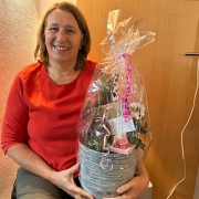 Seminarleiterin Anita sitzt im Seminarraum und hält ein Geschenk ihrer Teilnehmerinnen – Symbol für Wertschätzung und Verbundenheit.