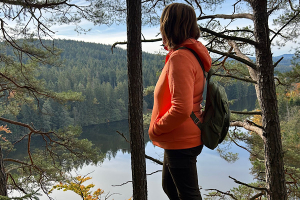 Die wichtigsten Tools 2026 für Veränderundwillige „Anita Griebl mit Rucksack steht inmitten der Natur und blickt auf einen ruhigen See, umgeben von Bäumen – Symbol für Innenschau, emotionale Klarheit und Tools für Veränderungsfreudige
