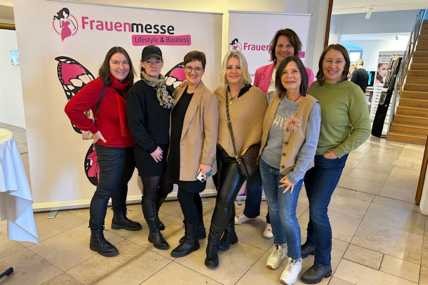 Sieben Unternehmerinnen auf der Frauenmesse in Straubing, gemeinsam vor dem Messe‑Plakat – ein besonderer Moment voller Austausch und Inspiration.