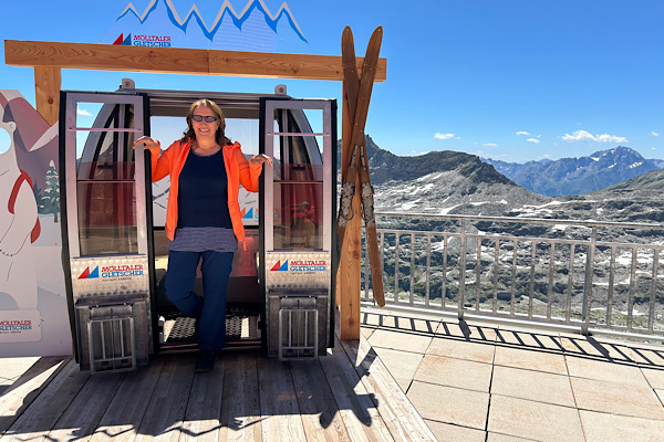 Anita Griebl steht auf dem Großglockner vor einer stationierten Gondel an einer Aussichtsplattform.