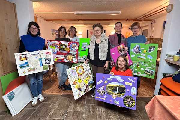 Sieben Frauen stehen in einer Gruppe und halten ihre gestalteten Visionsplakate vor sich.