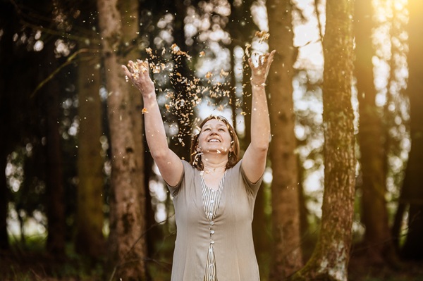 Anita Griebl steht im Wald und streut Flitter über sich. Ein Zeichen für Freiheit und Füle.