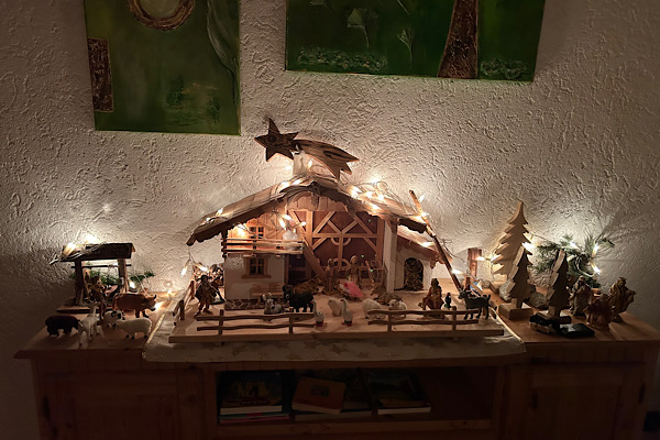 Eine große Holzkrippe mit vielen warm leuchtenden Lichtern.