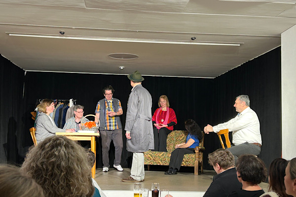 Theaterszene in Waltendorf mit Schauspielerinnen und Schauspielern auf der Bühne.