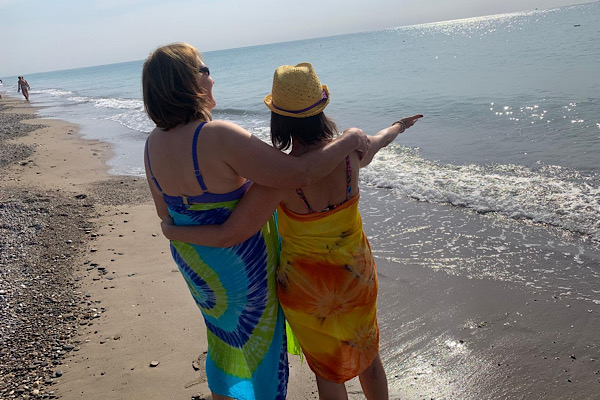 Zwei Frauen stehen am Meer und schauen gemeinsam in die Weite; ein sanfter Moment von Verbindung, Lebensfreude und zurückkehrender Energie.