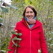 Anita Griebl geht lächelnd durch den Wald und blickt in die Kamera.