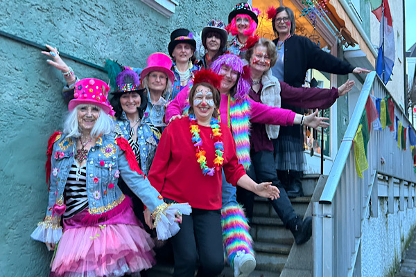 Zehn Frauen als Gute‑Laune‑Engel verkleidet, gemeinsam auf einer Treppe fotografiert – ein farbenfroher Moment voller Lachen und Freundschaft.