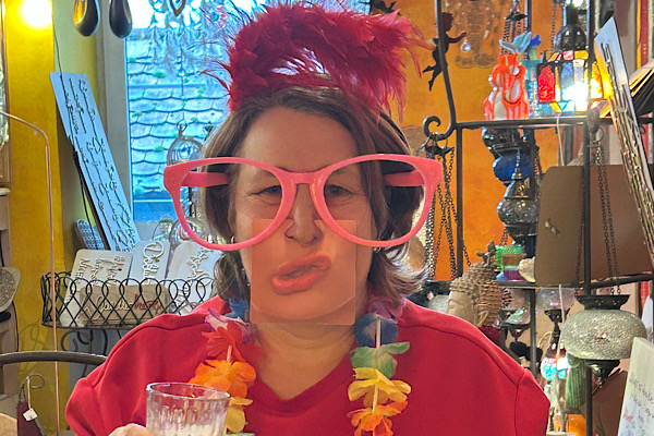 Anita Griebl trägt eine übergroße rosarote Brille und ein lustiges Mundpuzzle an der Nase – ein humorvoller Moment aus der 21‑Tage‑Challenge ‚Lebensenergie und innere Freude‘.