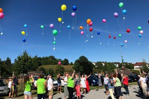 Treffpunkt Lebensfreude Menschen lassen bunte Luftballons in den Himmel steigen – ein Symbol für Leichtigkeit, Gemeinschaft und Lebensfreude.