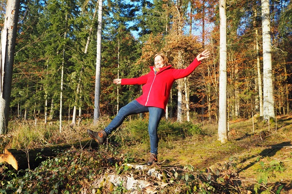 Anita Griebl in roter Jacke stolpert im Wald – Symbol dafür, was Persönlichkeitsstärkung nicht ist: Perfektion oder Härte.