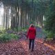 Anita Griebl in roter Jacke geht achtsam durch den herbstlichen Wald – Symbol für Persönlichkeitsstärkung und innere Klarheit.