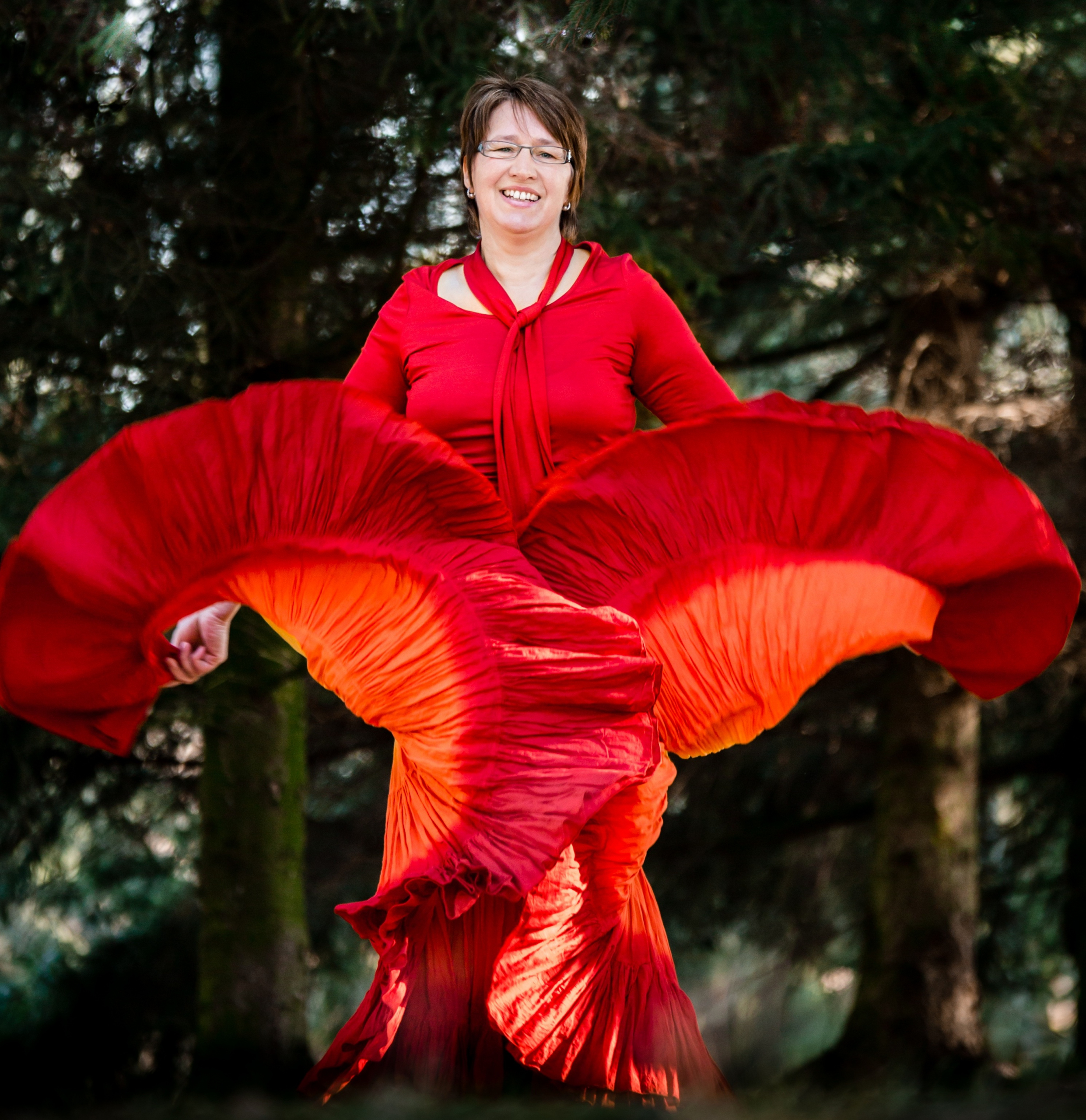 Anita Griebl tanzt in einem roten Kleid mit Brille – ein Bild ihrer früheren, kontrollierten Energie vor ihrer Transformation.
