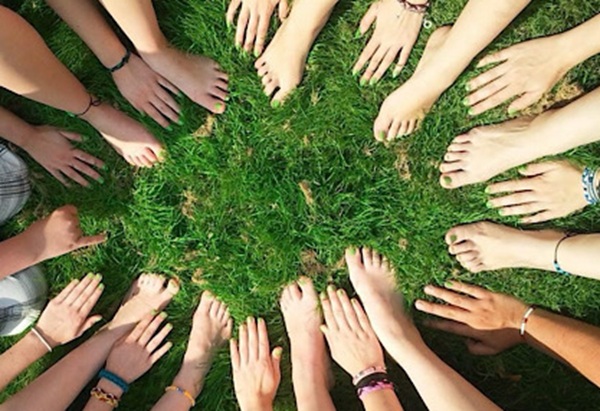 Mehrere Hände und Füße stehen im Kreis auf dem Boden, als Symbol für gemeinsame Aufstellungsarbeit.