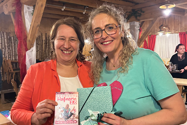Anita zeigt die Autogrammkarte, während Michaela Hafner das Geschenk in den Händen hält – ein gemeinsamer Moment nach ihrem Bühnenprogramm.
