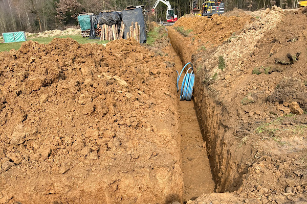 Grabungsarbeiten für die neue Wasserleitung, im Hintergrund stehen Baumaschinen.