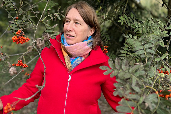 Anita Griebl steht in der Natur, schaut seitlich skeptisch in die Ferne.