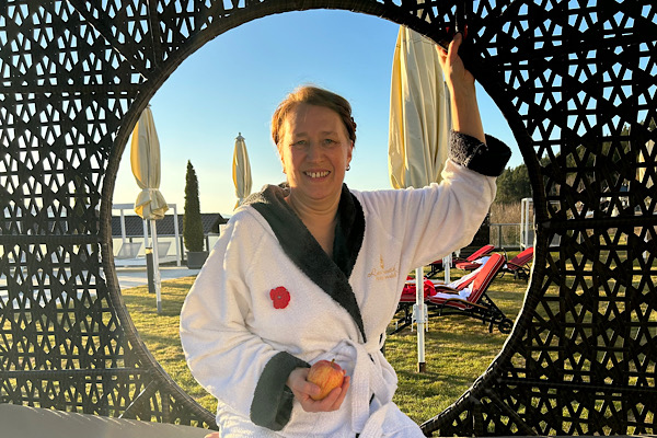 Anita sitzt entspannt im Korbhaus, hinter ihr leuchtet die Sonne durch die runde Öffnung und schafft ein warmes Urlaubslicht.