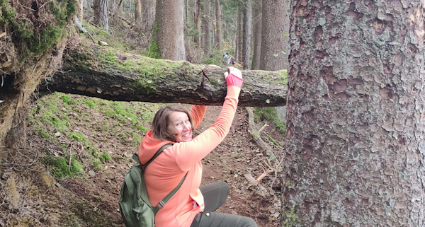 Anita Griebl zwängt sich unter einem umgestürzten Baumstamm hindurch – ein Symbol für den Weg durch innere Hindernisse.