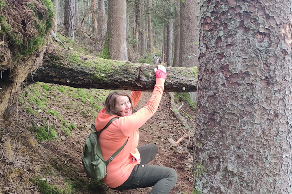 Anita Griebl zwängt sich unter einem umgestürzten Baumstamm hindurch – ein Symbol für den Weg durch innere Hindernisse.