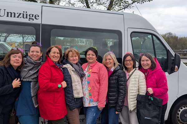 Unser achtköpfiges Team posiert fröhlich vor dem Bus, mit dem wir nach Baden‑Baden gefahren sind.